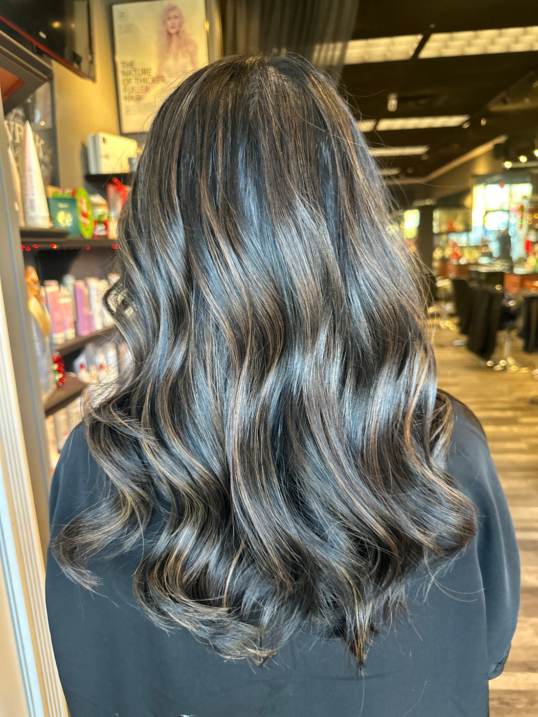 Long layered brunette hair with soft waves and a cool glossy finish after a cut and color service